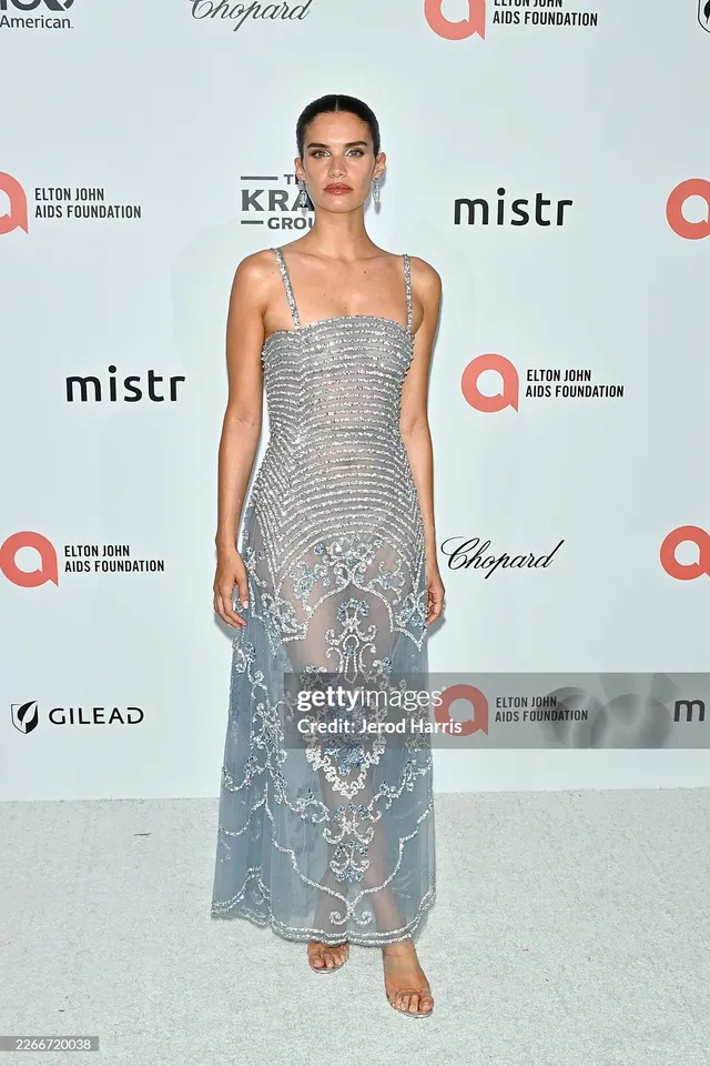 Sara Sampaio wearing heeled sandals beneath a long silver embellished dress.