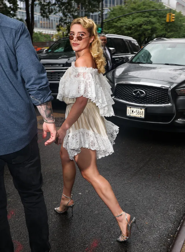Florence Pugh walking in a white dress and pale heels.