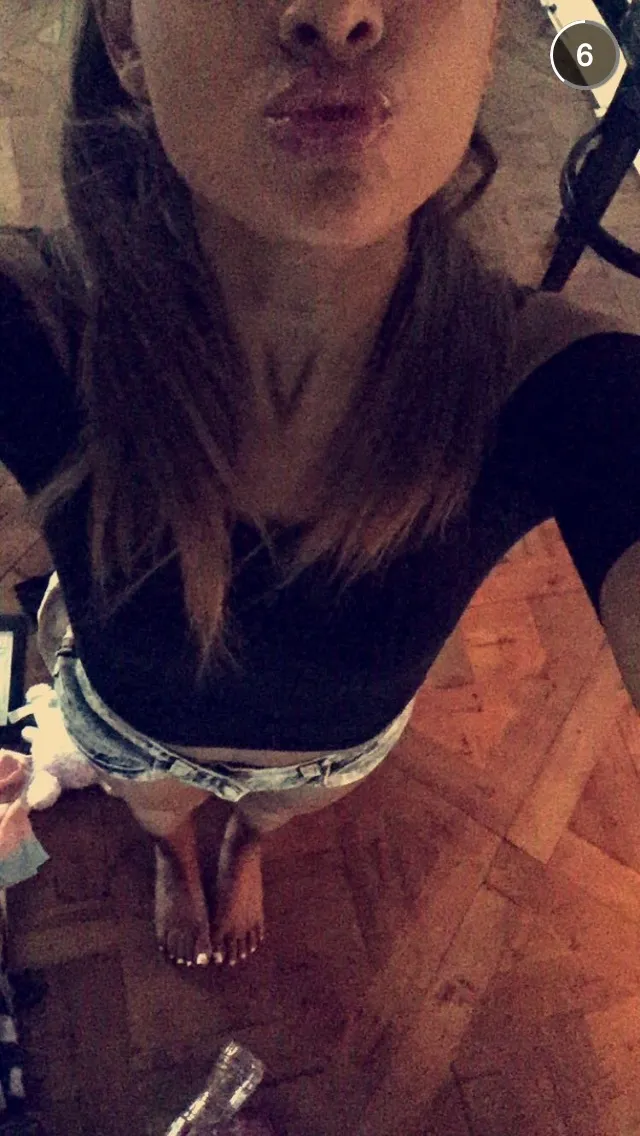 Ariana Grande a downward selfie showing her bare feet on a wooden floor.