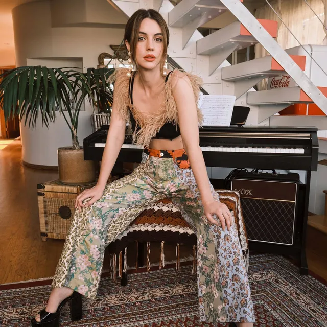 Adelaide Kane sitting beside a piano during a portrait shoot.