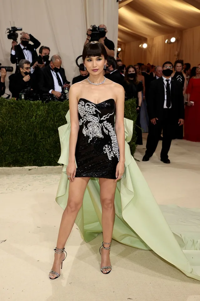 Gemma Chan posing in an embellished minidress with a pale train.