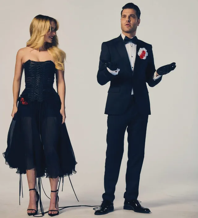 Mckenna Grace posing beside another person in a dark dress and heels.