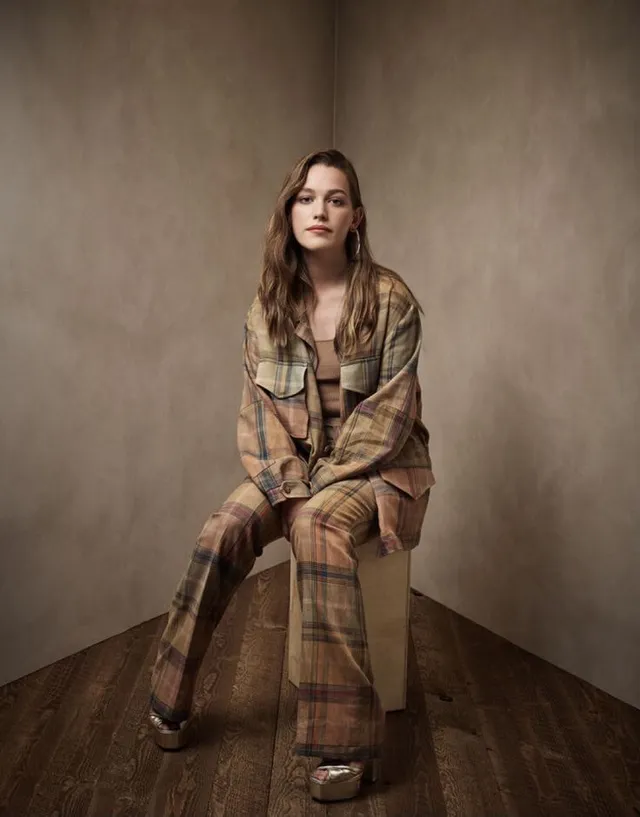 Victoria Pedretti sitting for a fashion portrait in a checked outfit.