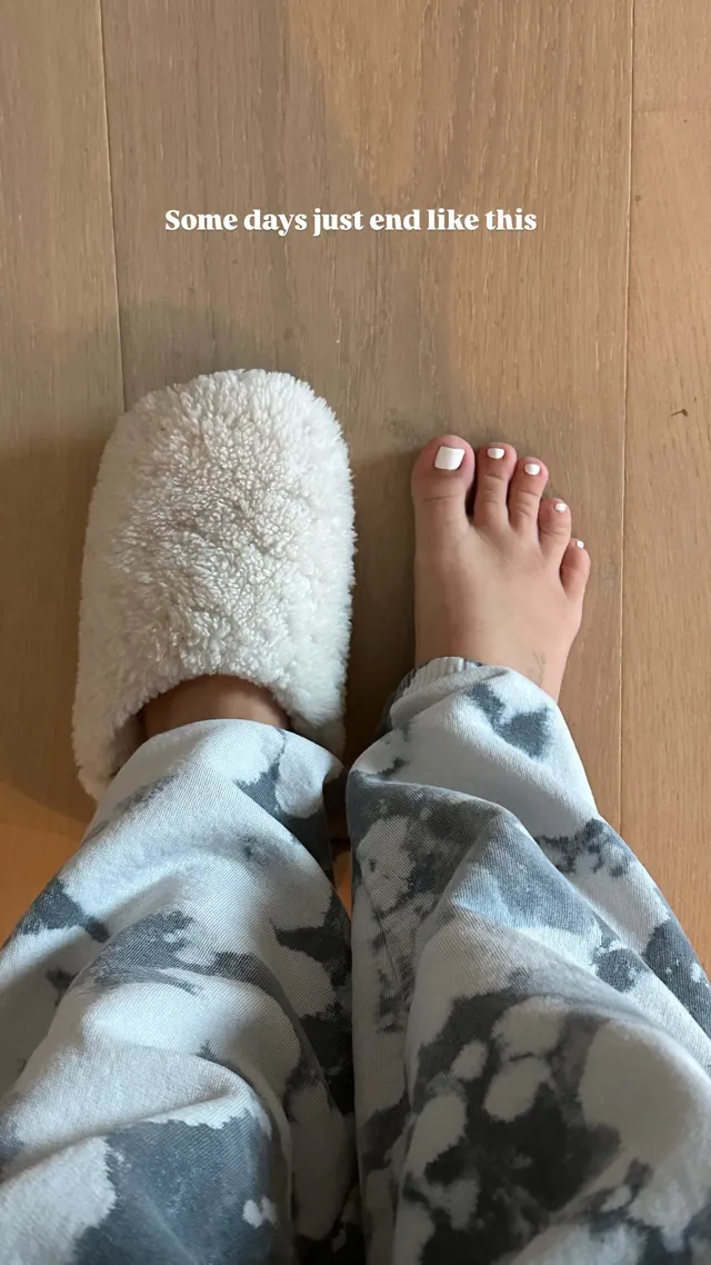 Ashley Tisdale resting a bare foot beside a soft slipper.