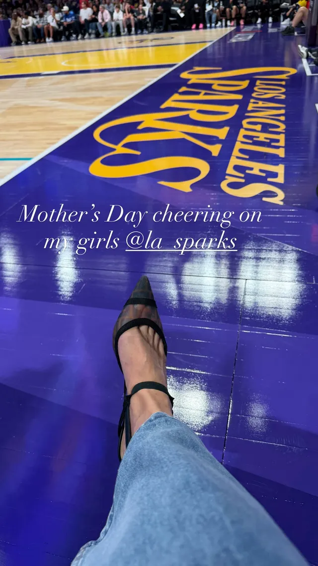 Sarah Michelle Gellar resting a black high-heeled sandal beside a basketball court.