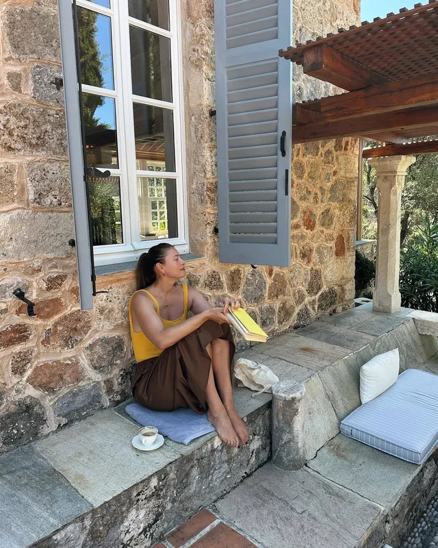 Maria Sharapova sitting barefoot on stone steps in a yellow top.