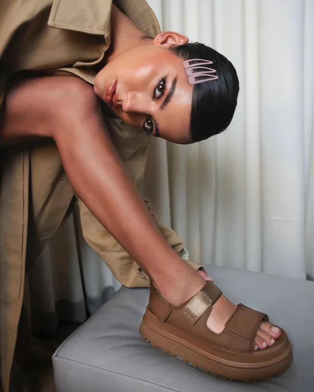 Isabela Merced wearing chunky brown platform sandals while leaning forward.