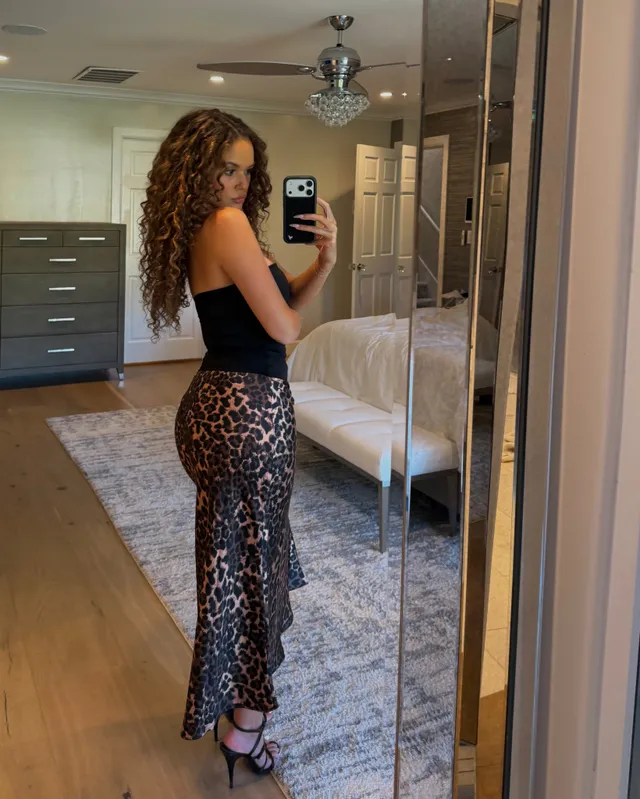 Madison Pettis taking a mirror selfie in a dark top, leopard-print trousers and black heels.