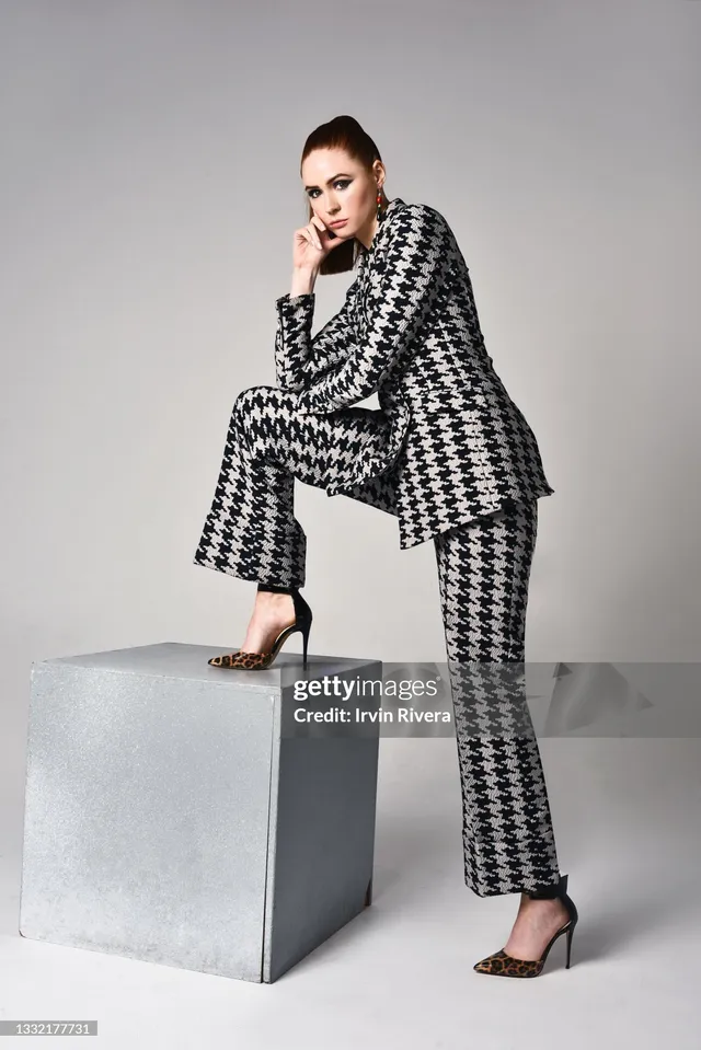 Karen Gillan posing in a patterned suit and heels for a studio portrait.