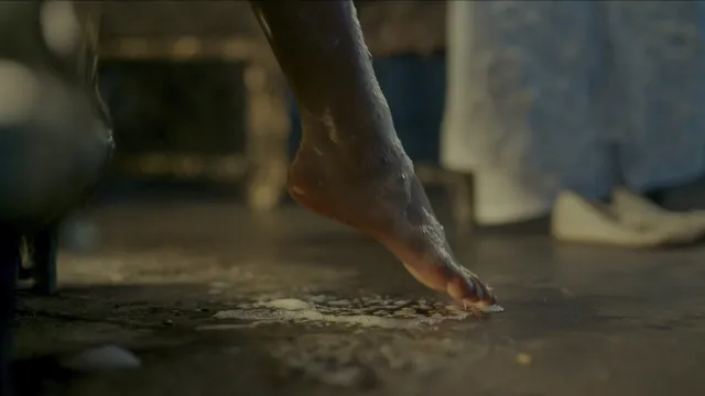 Freya Allan stepping barefoot across an indoor floor in a film scene.