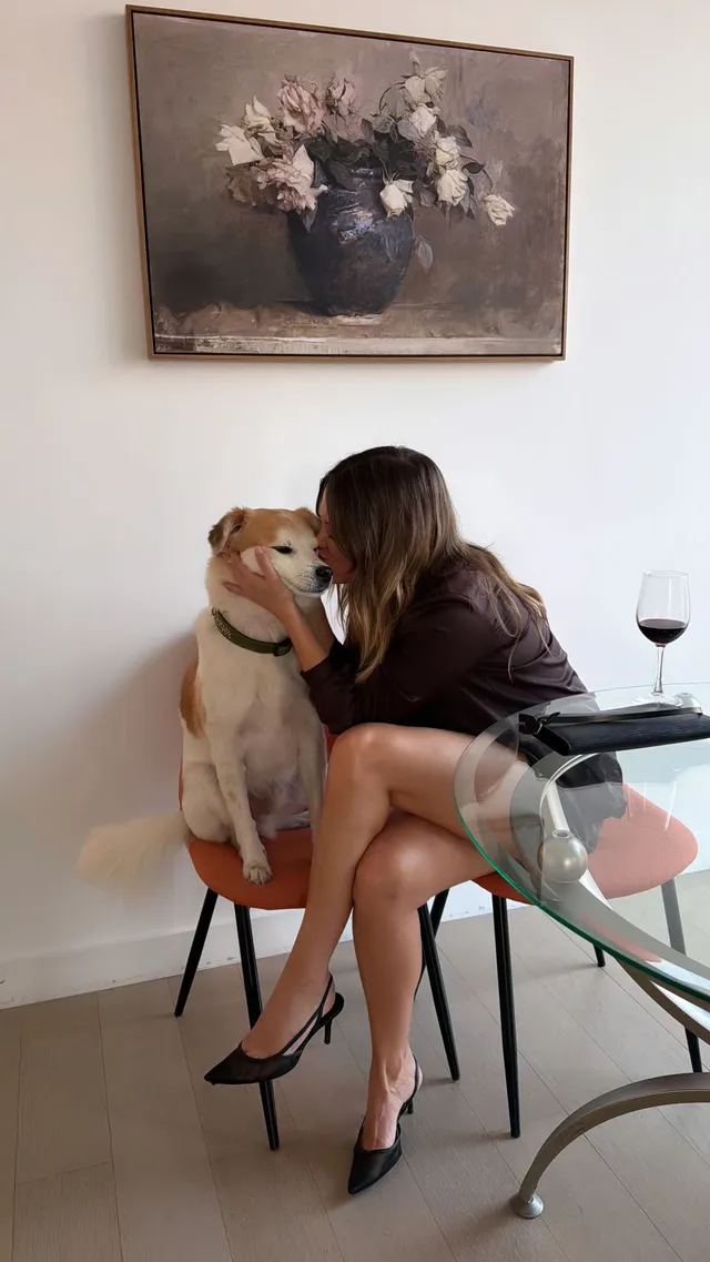 Olivia Holt sitting beside a dog in a chair wearing black pointed heels.