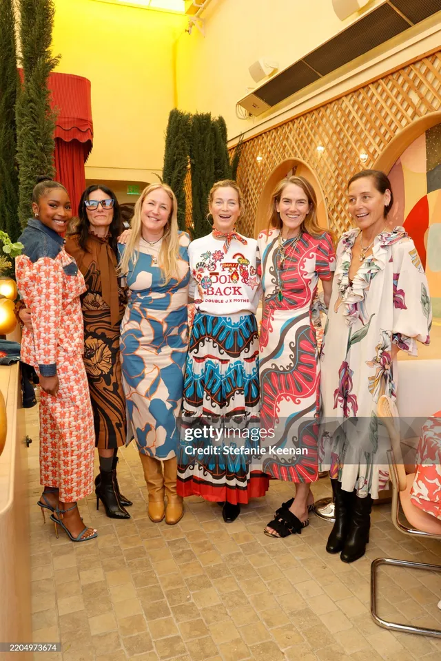 Carlacia Grant standing with guests in a patterned trouser suit and blue heels.