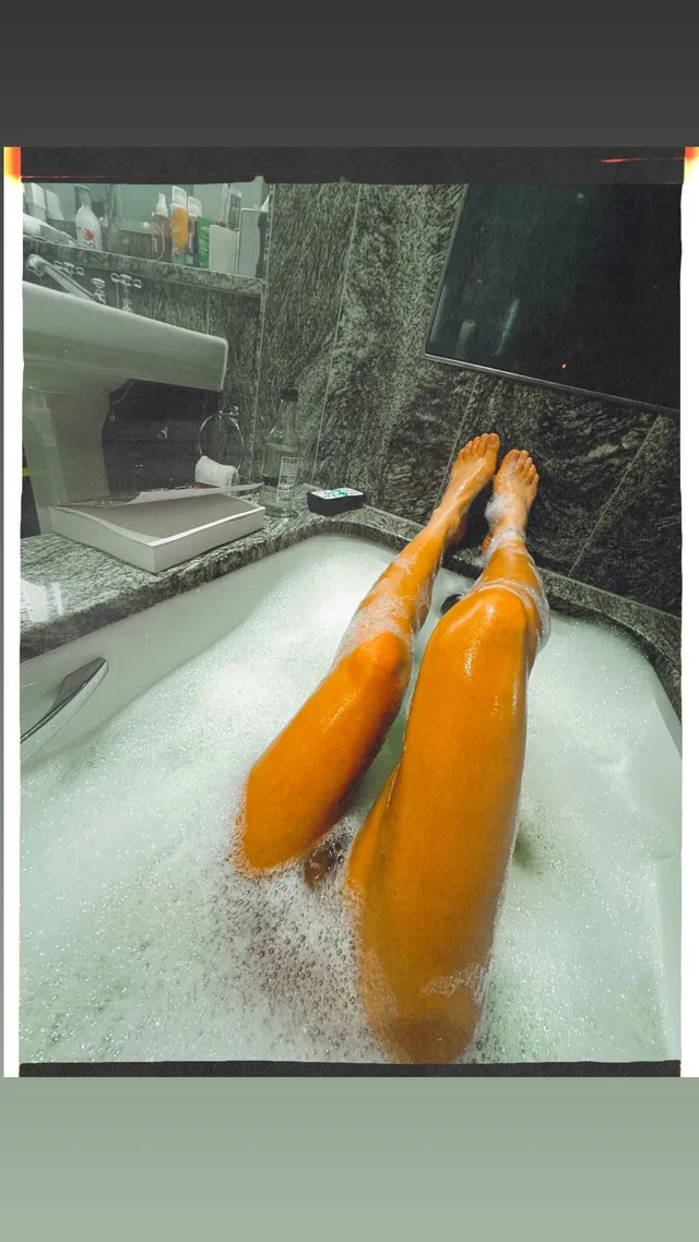 Sarah Shahi resting her bare feet in a bubble bath.