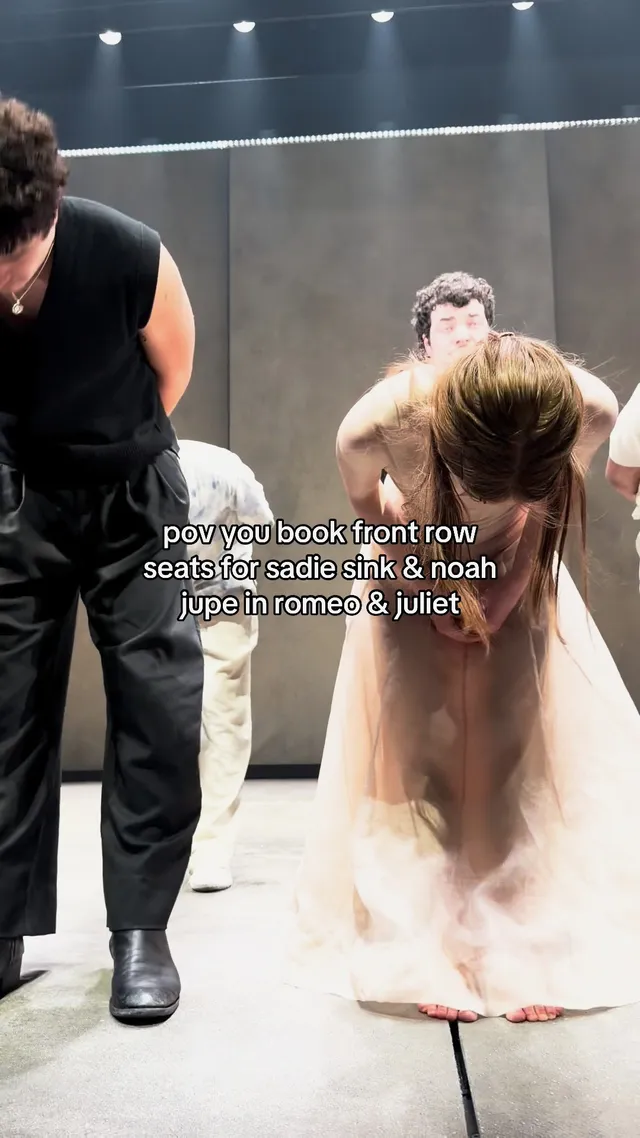 Sadie Sink bowing barefoot onstage in a long pale dress.