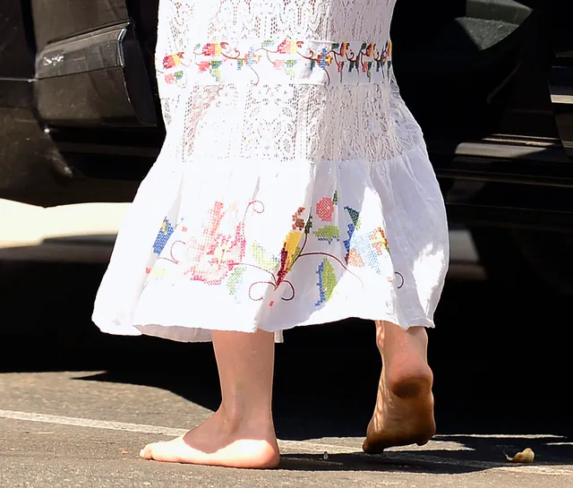 Isla Fisher a close-up of bare feet beneath a white floral dress.
