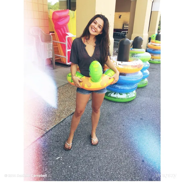 Danielle Campbell standing beside a shop display holding a pool float.