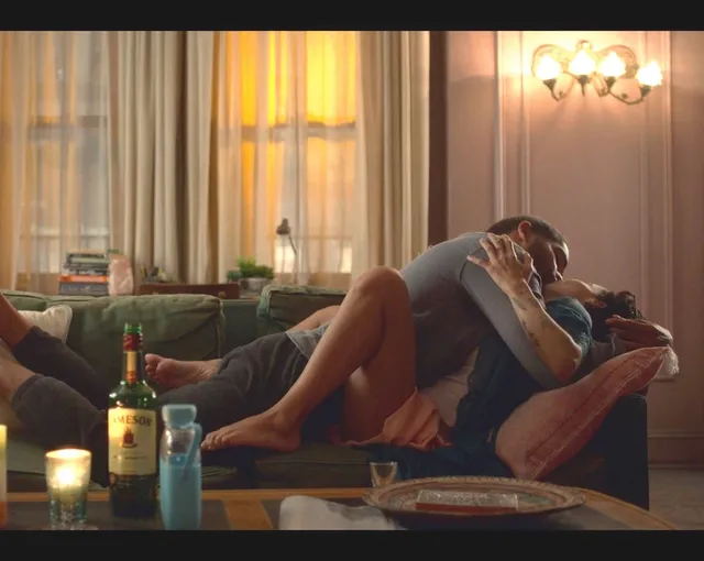 Zoë Kravitz reclining on a sofa beside a companion in a screen scene.