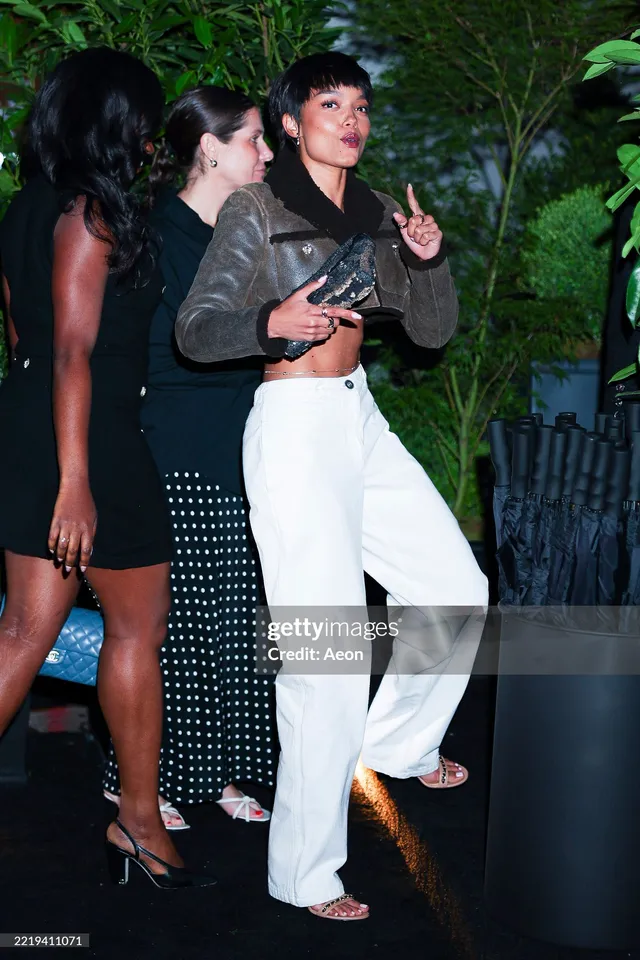 Whitney Peak standing with guests in white trousers and heels at an event.