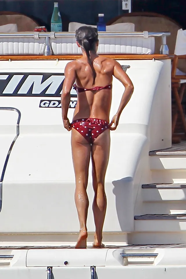 Alicia Vikander standing on a boat in a patterned swimsuit.