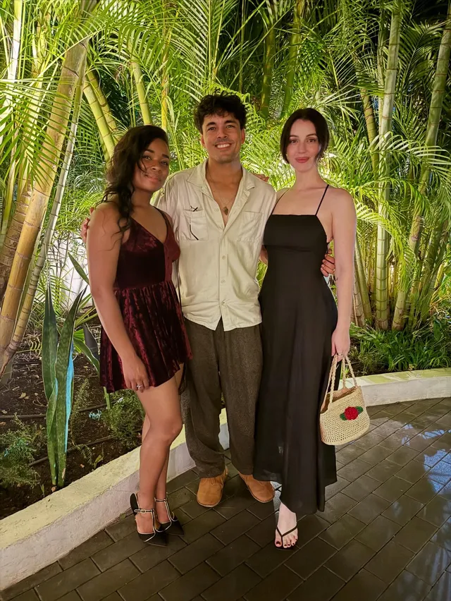 Adelaide Kane posing with companions outdoors in a dark dress.