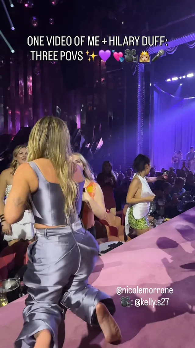 Hilary Duff appearing onstage in a silver dress and heels.