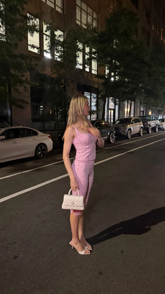 Eugenie Bouchard wearing pale heels and a pink fitted dress outdoors at night.