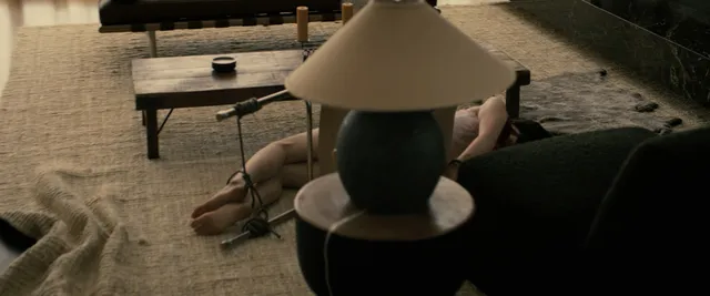 Sophie Thatcher reclining with bare feet visible on a sofa in a film scene.