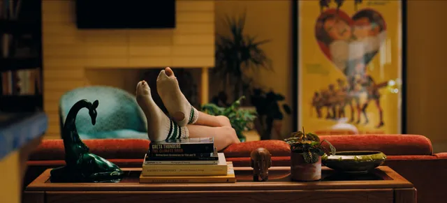 Zendaya: bare soles resting on stacked books beside a bed.