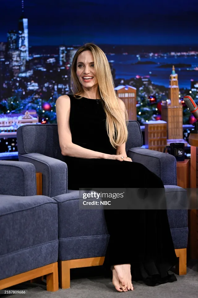 Angelina Jolie a seated talk show portrait in a black dress.