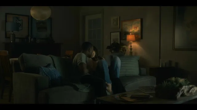 Victoria Pedretti sitting with a companion on a sofa during a screen scene.