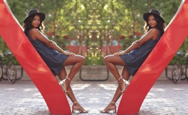 Greta Onieogou sitting in a red sculpture wearing a dark dress and strappy heels.