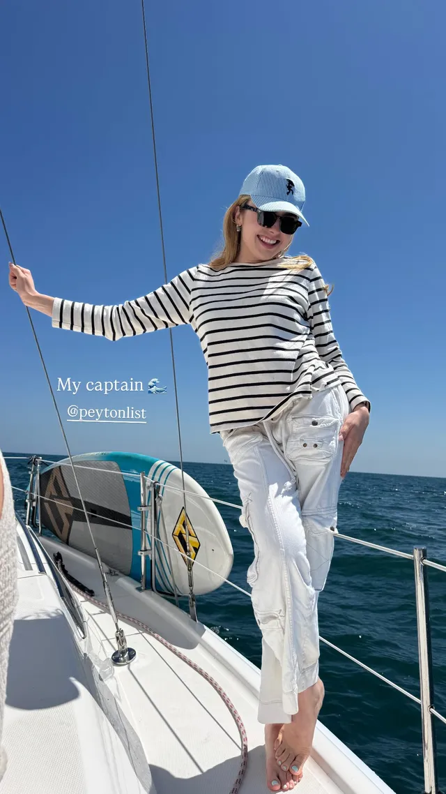 Peyton List standing barefoot on a sailboat in a striped top.