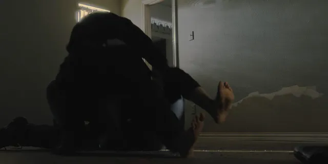 Zoe Saldaña sitting on a floor with her feet raised in a scene.