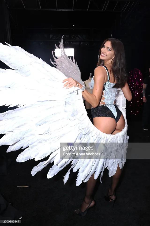Irina Shayk looking back in a winged runway outfit and heels.
