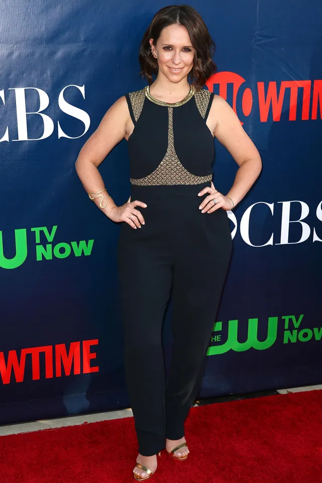 Jennifer Love Hewitt standing at an event in a black outfit and metallic heels.