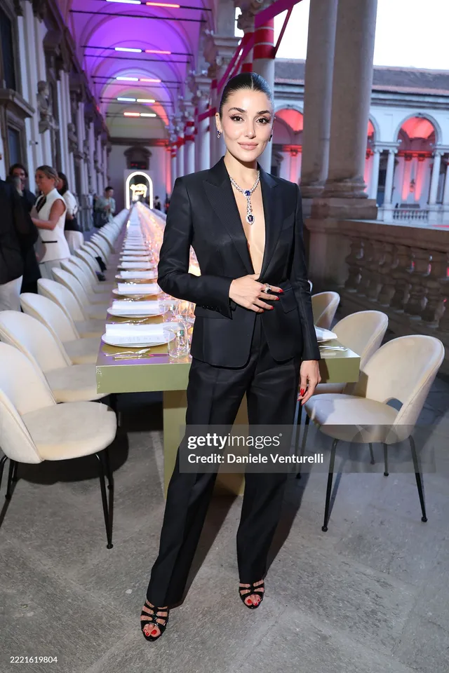 Hande Erçel wearing a black trouser suit and strappy heels.
