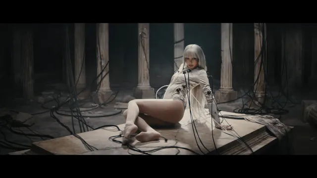 Lisa (Lalisa Manobal) sitting barefoot on a wooden platform during a dramatic screen scene.