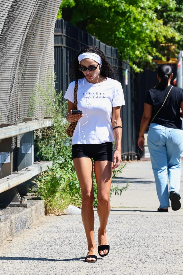 Zoë Kravitz walking outside in black shorts and mules.