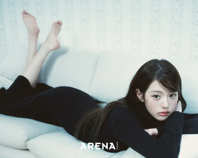 Jang Wonyoung lying on a pale sofa with bare feet raised.