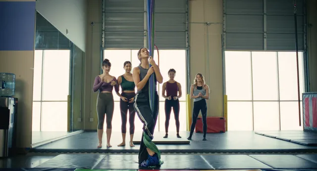 Bailee Madison standing barefoot in a mirrored dance studio.