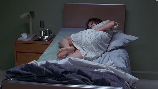 Angelina Jolie lying on a bed in a patterned outfit.