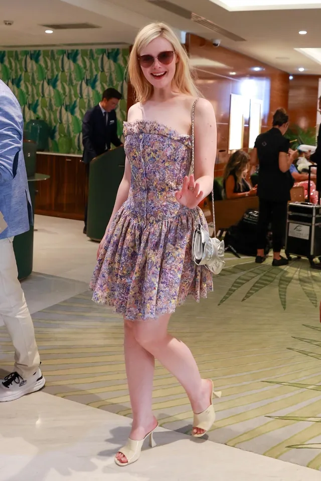 Elle Fanning walking in a floral dress and pale heeled sandals.
