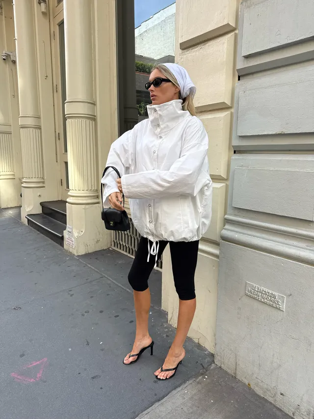 Elsa Hosk wearing black heeled sandals with a white jacket and cropped black leggings.