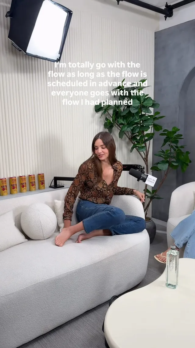 Miranda Kerr a seated barefoot pose on a white sofa.