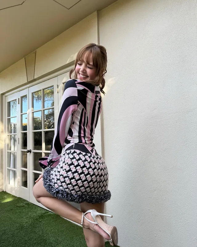 Lisa (Lalisa Manobal) wearing pale platform heels and a patterned skirt beside a lawn.