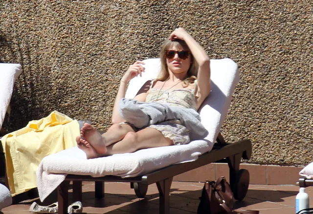 Taylor Swift reclining on an outdoor sun lounger.