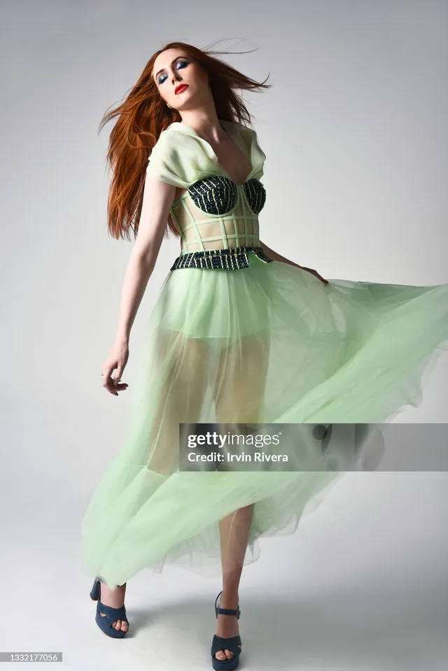 Karen Gillan posing in a green dress and black heels for a studio portrait.