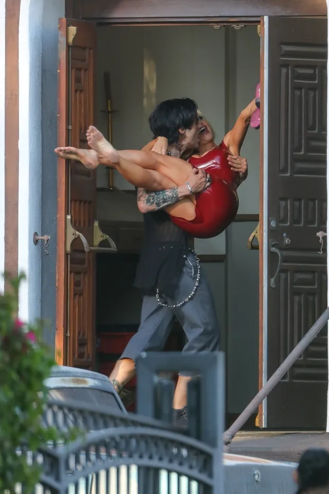 Lily James being lifted by another person with bare feet extended in a screen image.