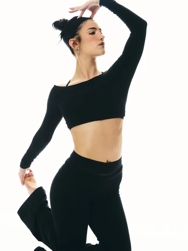 Charli D’Amelio posing in a black dance outfit for a studio portrait.