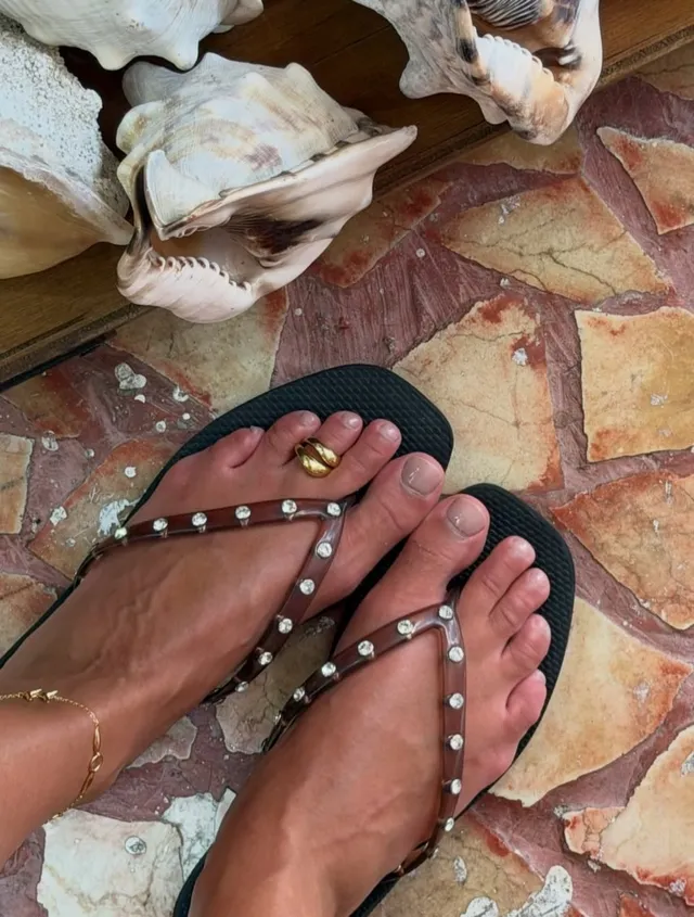 Taylor Hill showing jewelled flat sandals beside a dog.